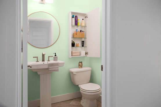 Bathroom with shelving cabinet hung above toilet. 